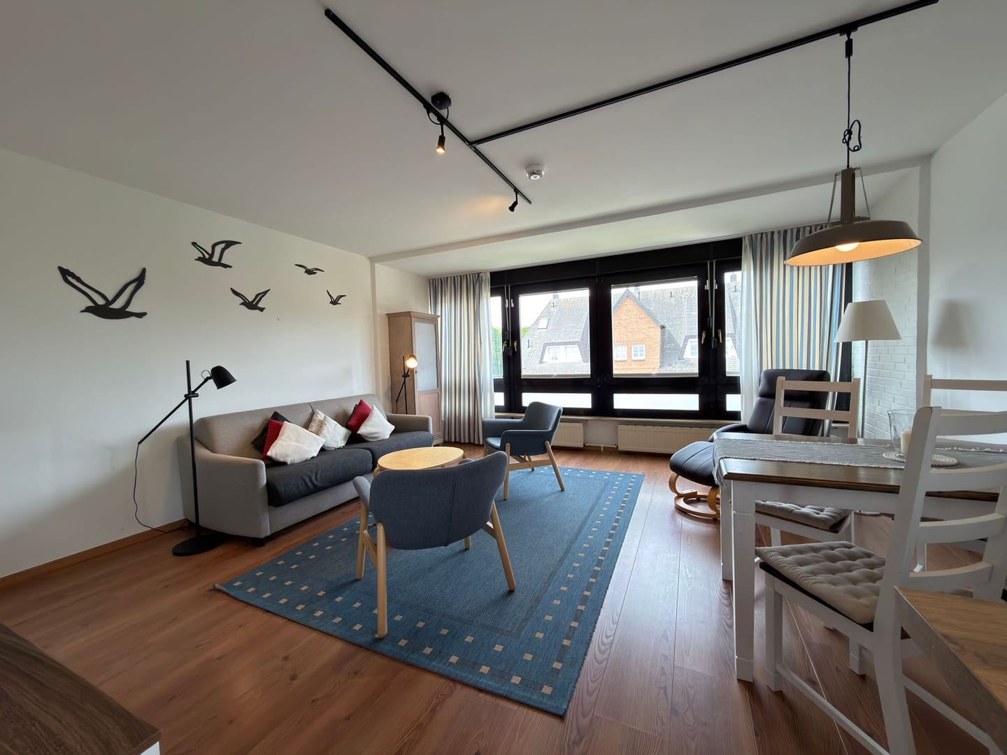 Heller Wohnbereich mit Sofa, großer Fensterfront und maritimer Möwen-Wanddeko